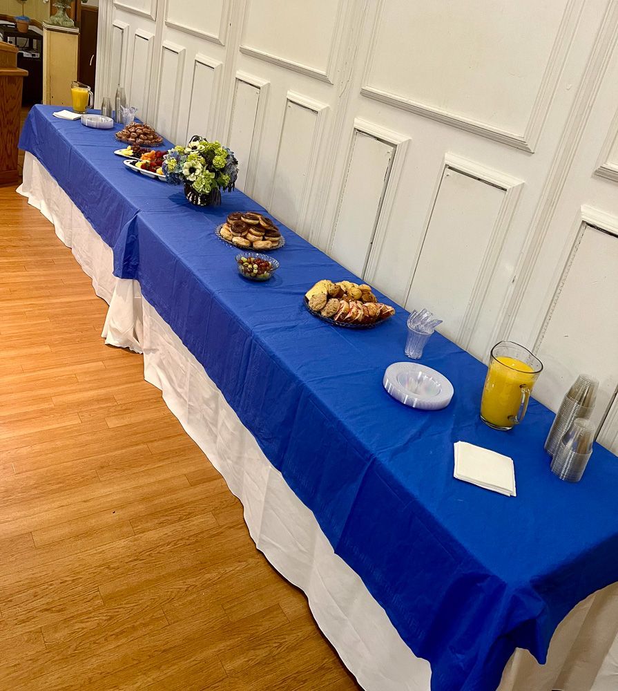 A long table with a blue table cloth and food on it