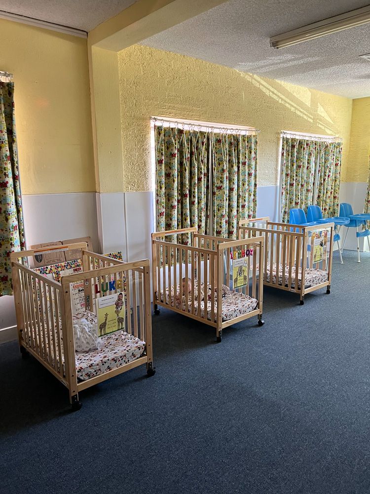Three wooden cribs are lined up in a room.