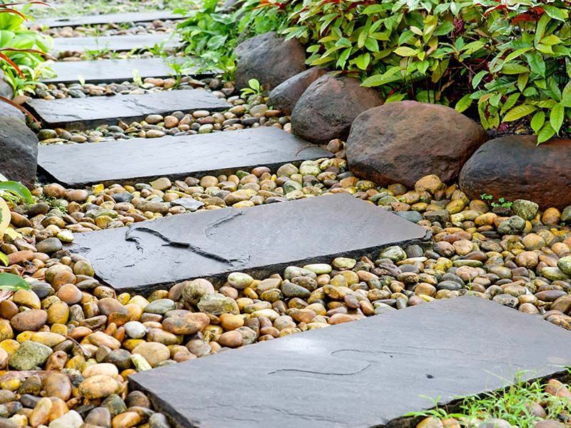 A stone walkway in a garden surrounded by rocks and plants.