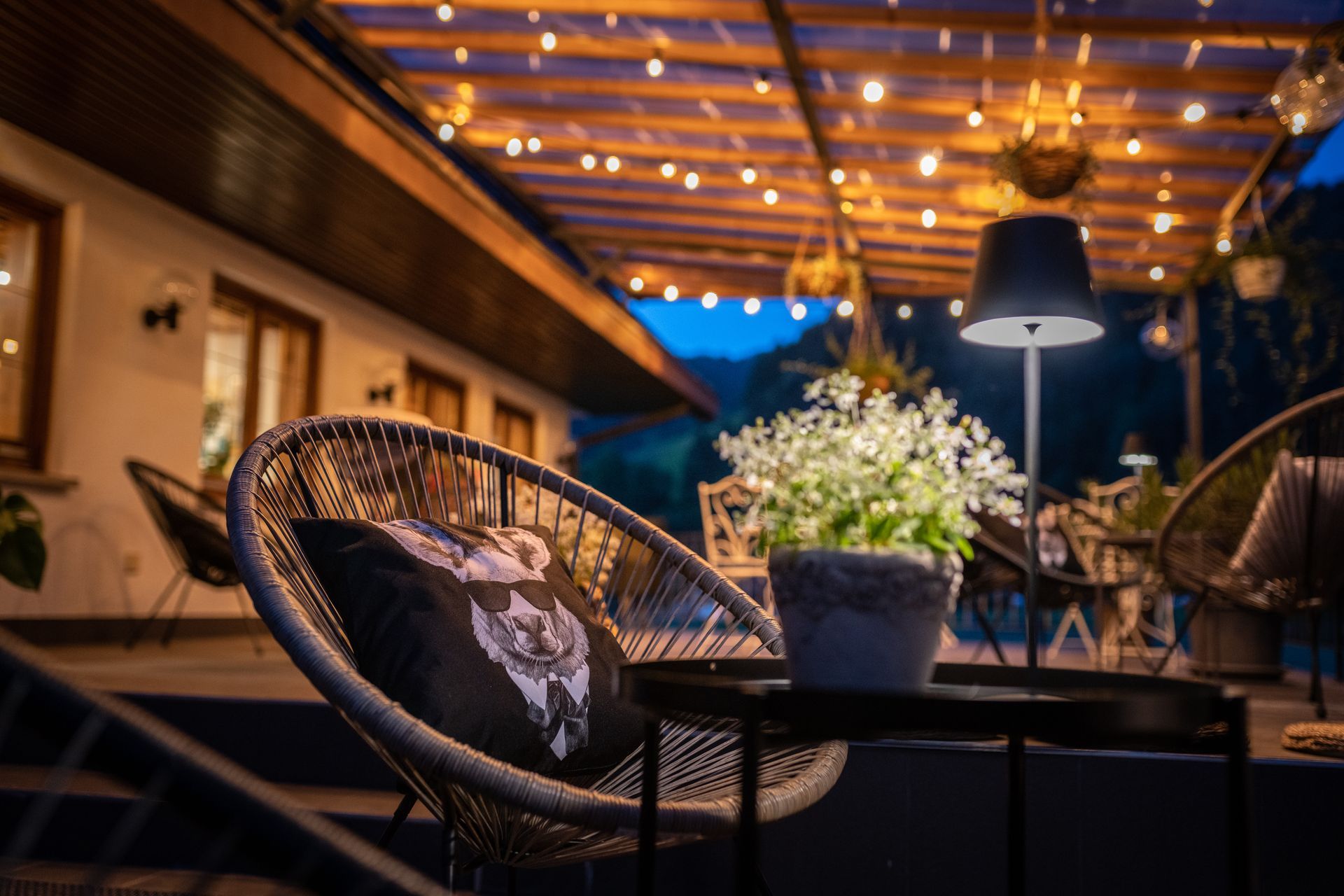 A patio with chairs , a table and a lamp at night.