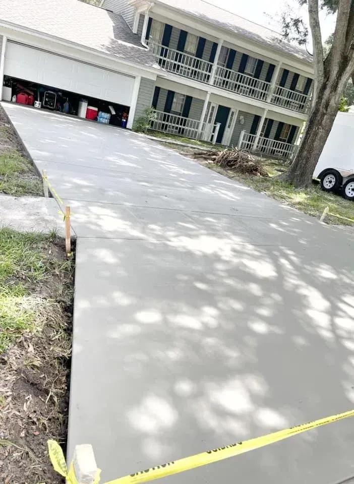 Newly poured concrete driveway leading up to a two-story house.
