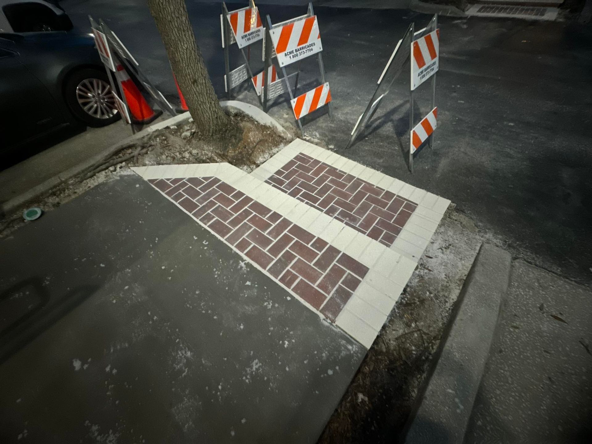 Brick steps with white trim next to a tree, with construction barriers in the background.