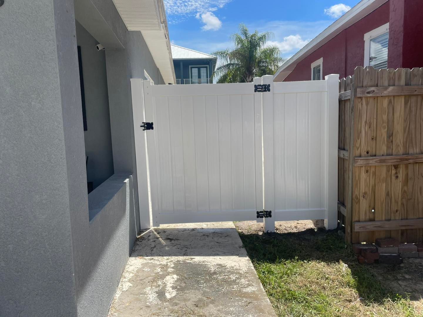 White vinyl gate between two buildings; a sidewalk leads to it.