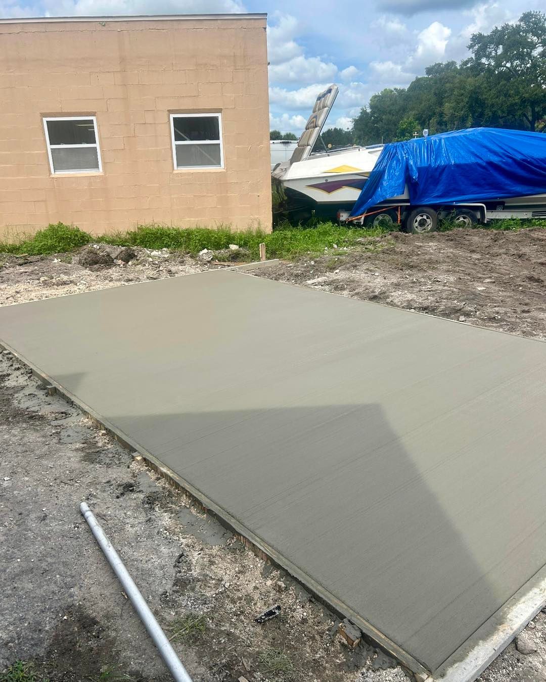 Newly poured concrete slab with a building and boat in the background.