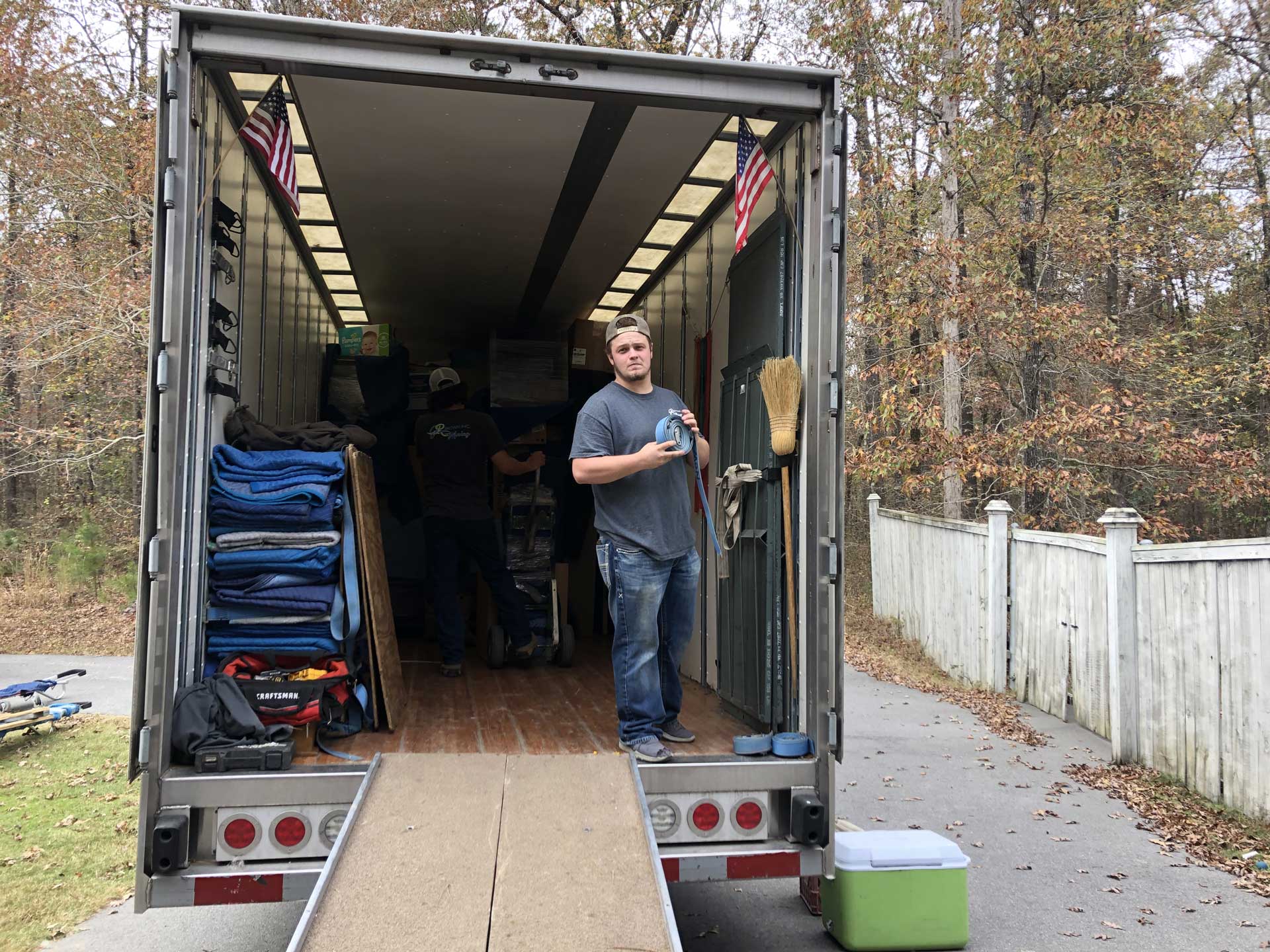 A man is standing in the back of a moving truck.