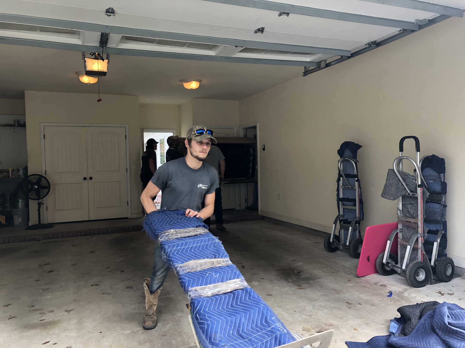 A man is carrying a large piece of furniture in a garage.