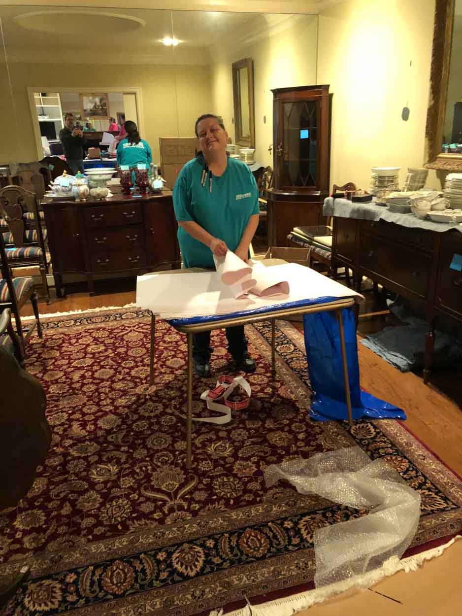 A woman is standing next to a table in a living room.