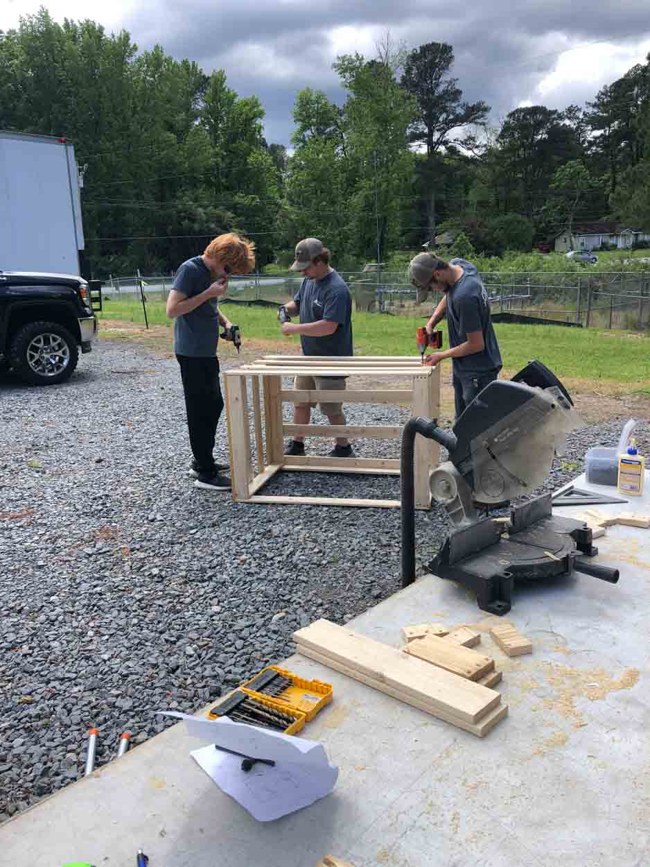 A group of people are working on a piece of wood.