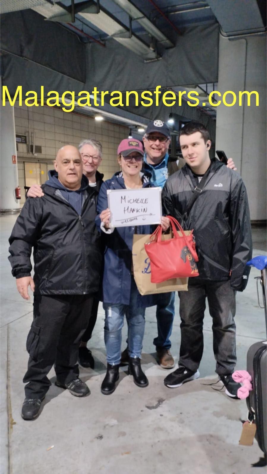 A group of people standing next to each other holding a sign that says malagatransfers.com