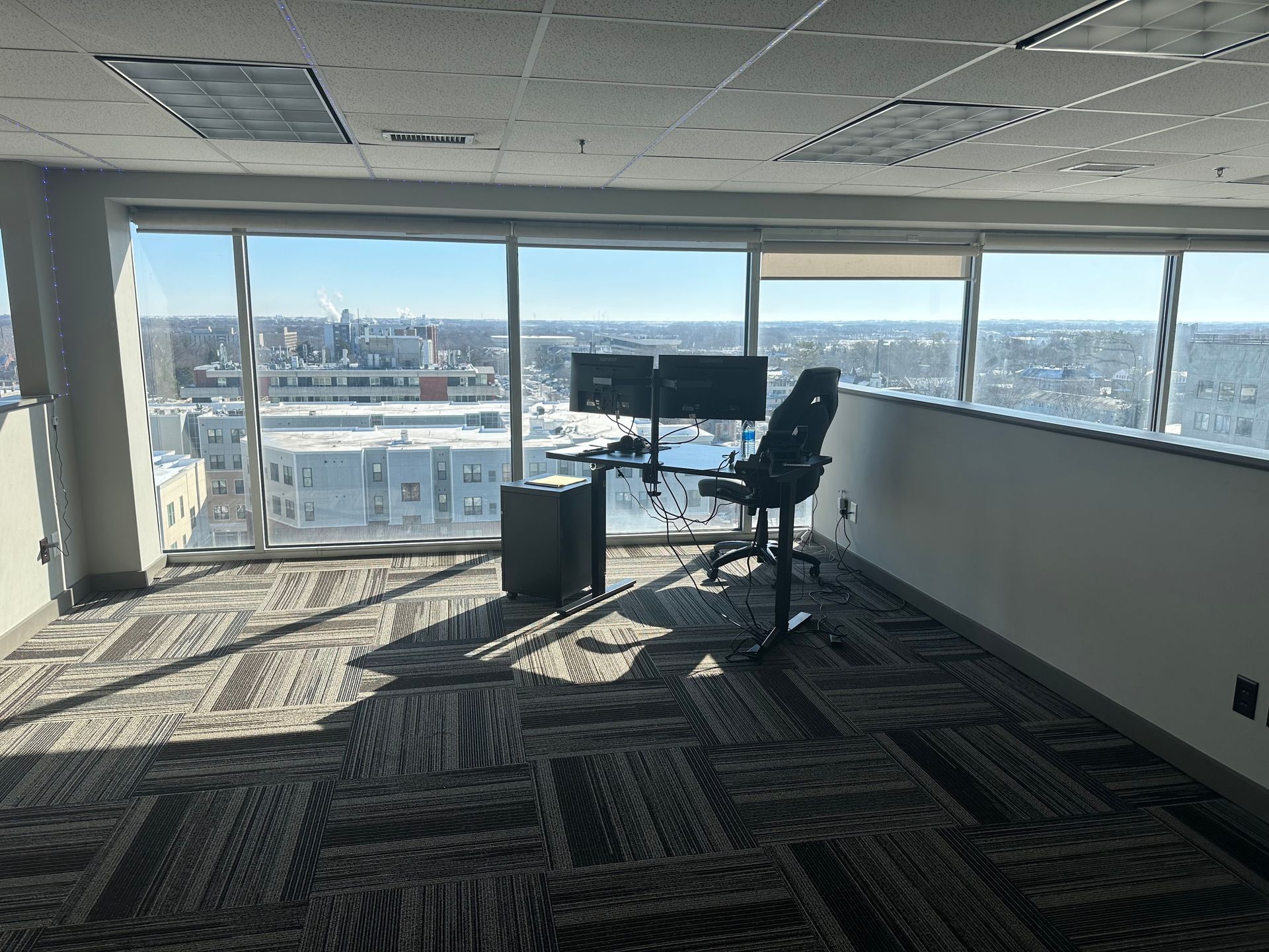 An empty office with a desk and chair and a view of the city.
