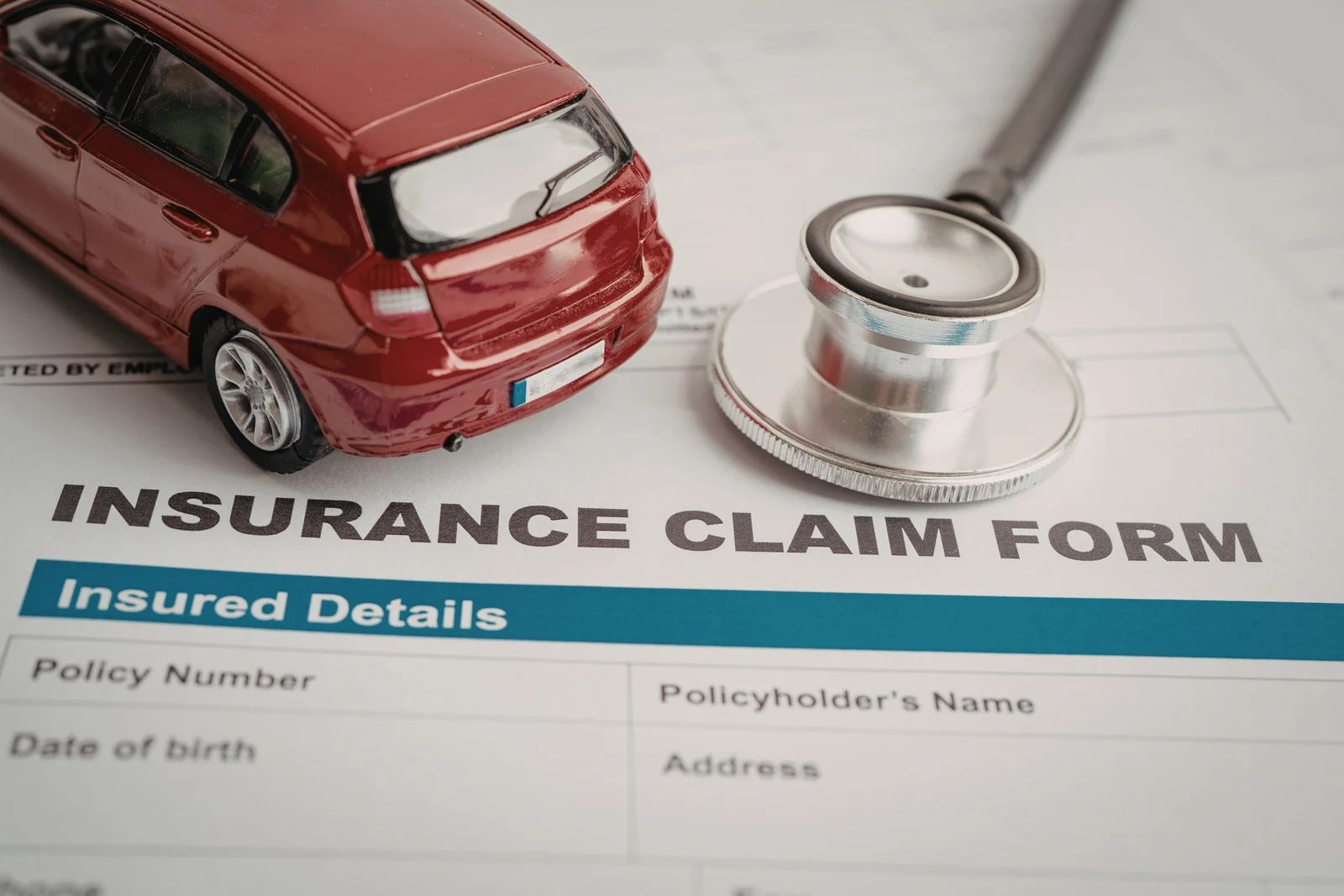 Red car and stethoscope on an insurance claim form
