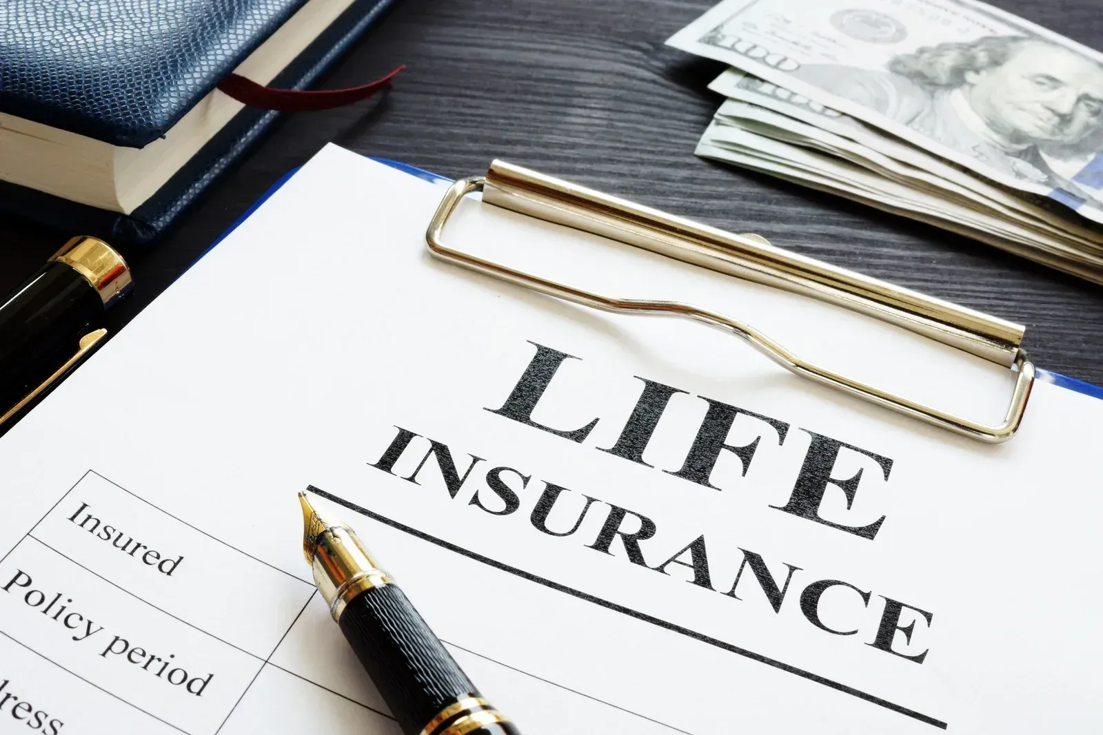 A clipboard with a pen on top of it that says life insurance.