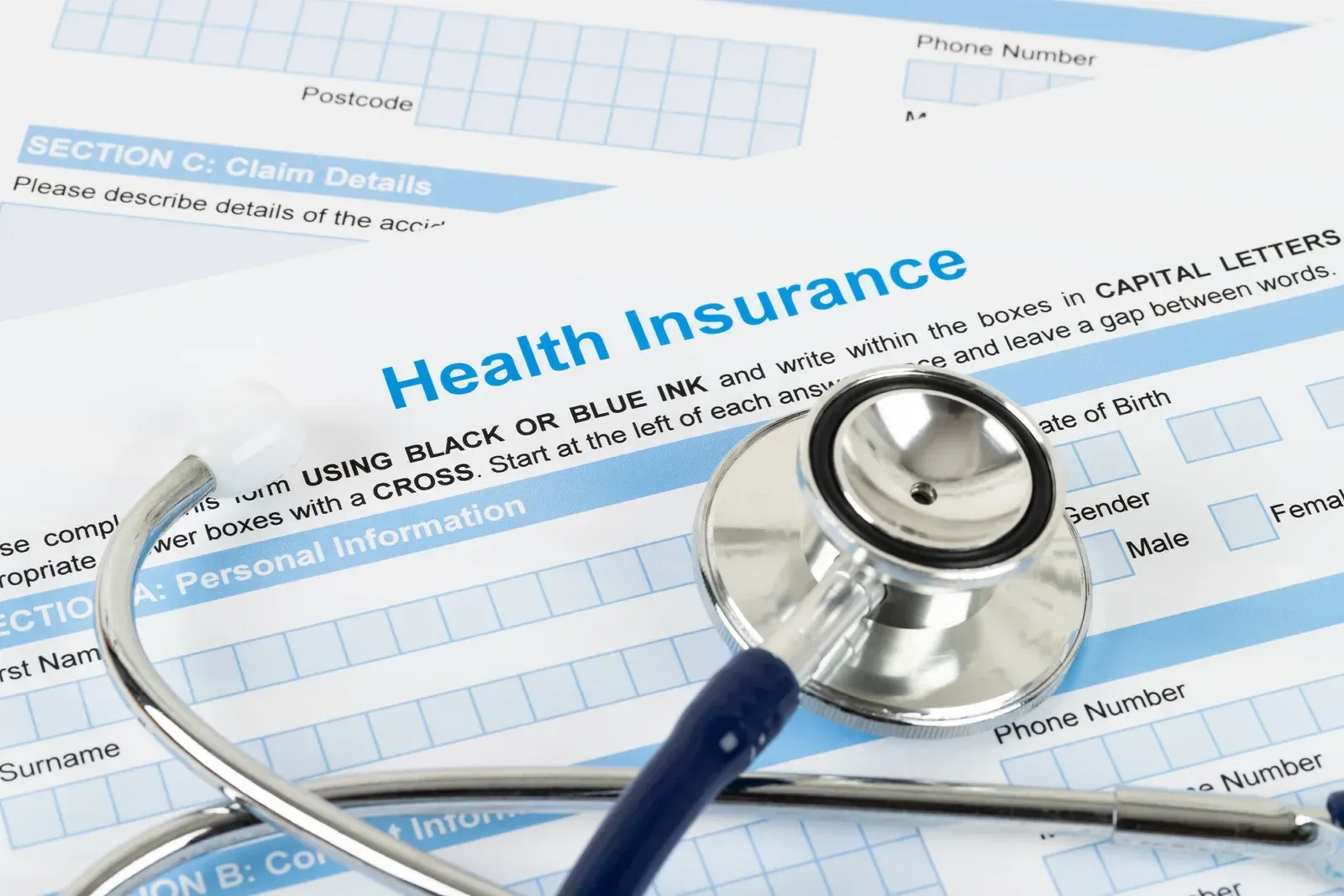 A stethoscope sits on top of a health insurance form