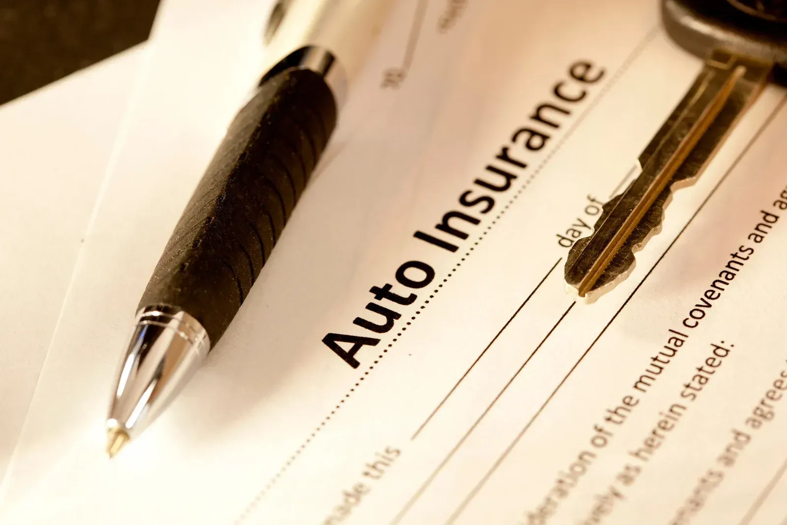 A pen rests on top of an auto insurance form
