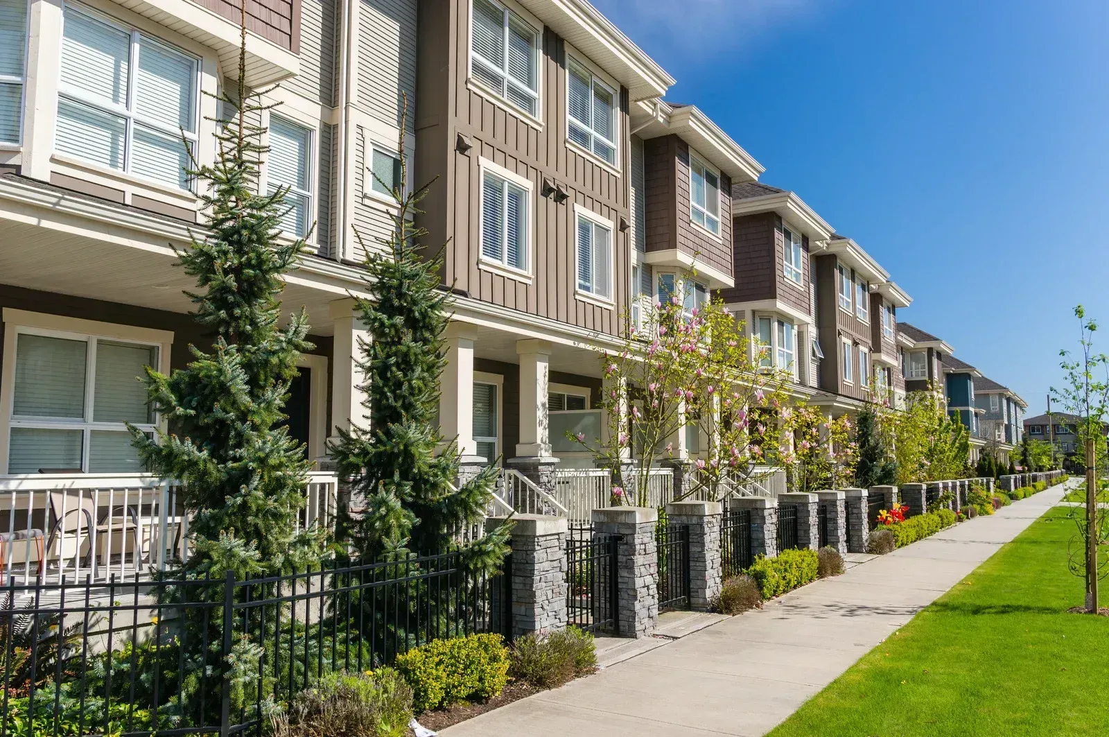 A row of apartment buildings with a sidewalk in front of them.