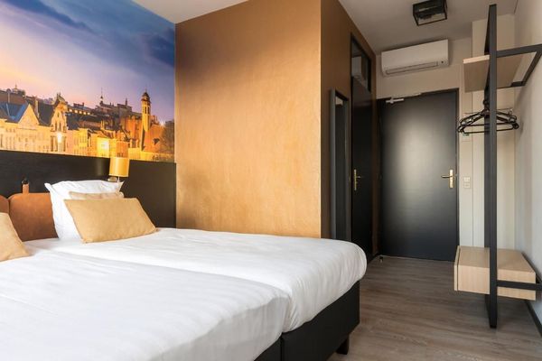 Een hotelkamer met twee bedden en een schilderij aan de muur.