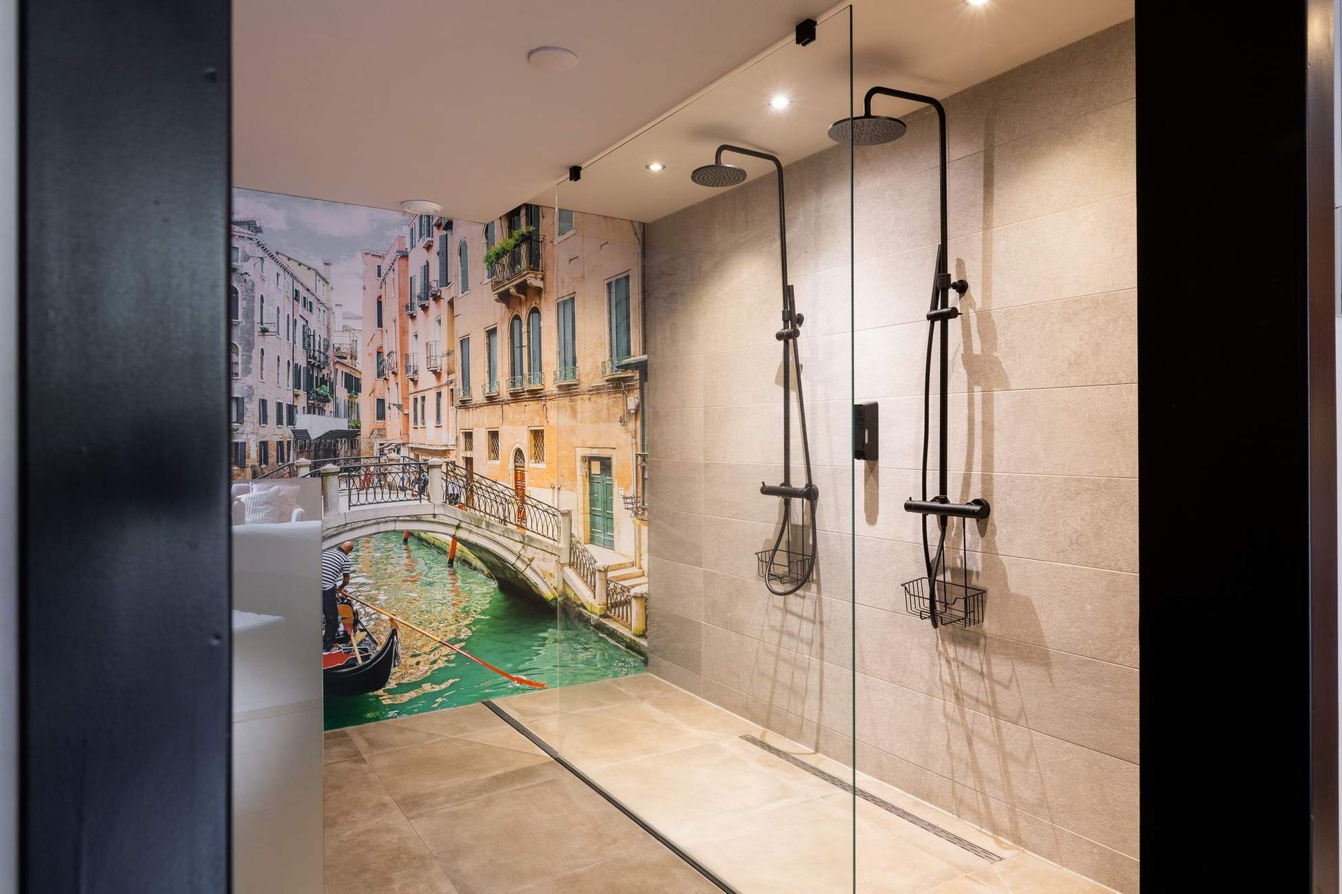 Inloopdouche met een muurschildering van Venetië, drie douchekoppen en een grijze tegelmuur.