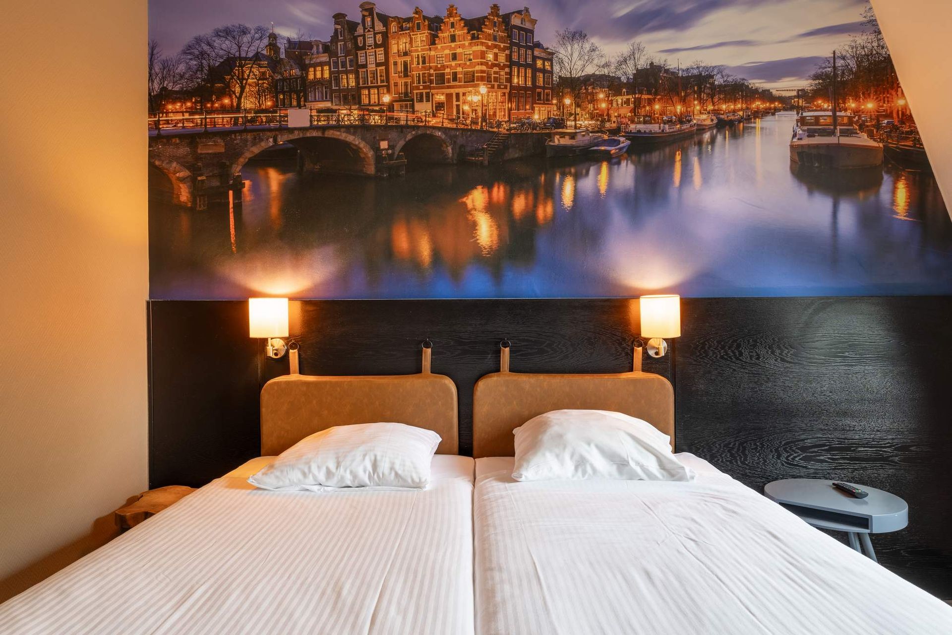 Een hotelkamer met twee bedden en een schilderij aan de muur.