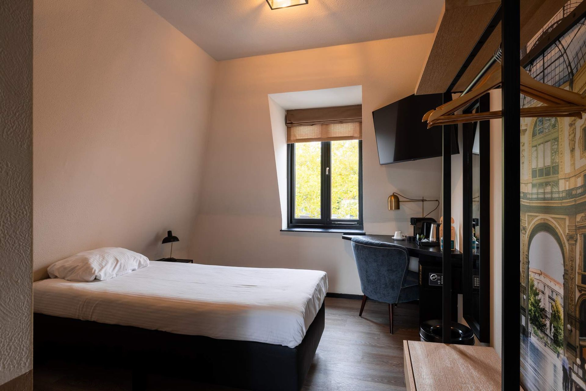 Een hotelkamer met een eenpersoonsbed en een foto van de skyline van een stad aan de muur.