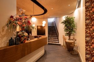 Een hotelkamer met een groot bed, stoelen en een schilderij aan de muur.