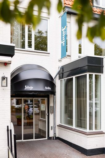 Een hotelkamer met twee bedden en een schilderij aan de muur.