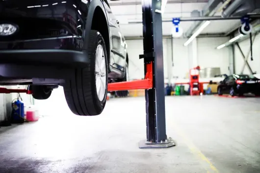 A car is sitting on a lift in a garage.