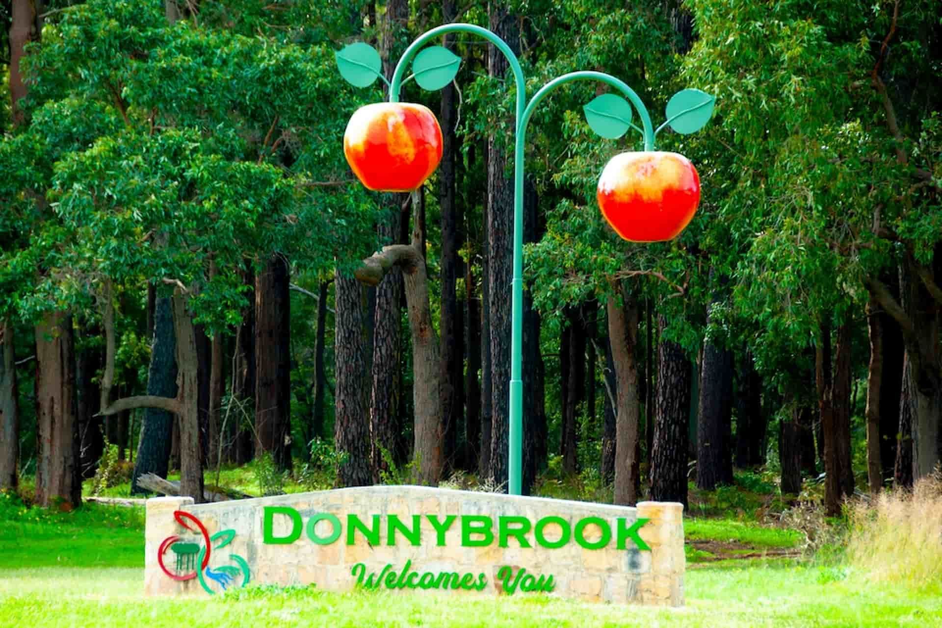 A Sign That Says Donnybrook Welcomes You In Front Of A Forest — Tom Thumbs Tree Works In Donnybrook, QLD