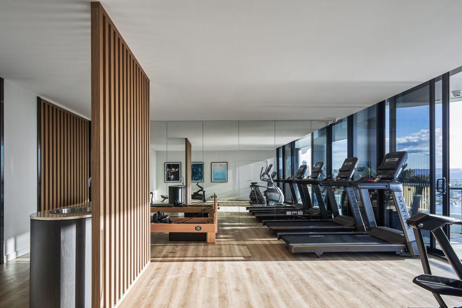 A Gym With Treadmills, Exercise Bikes, And A Large Mirror — Harrison Development Group In Surfers Paradise, QLD