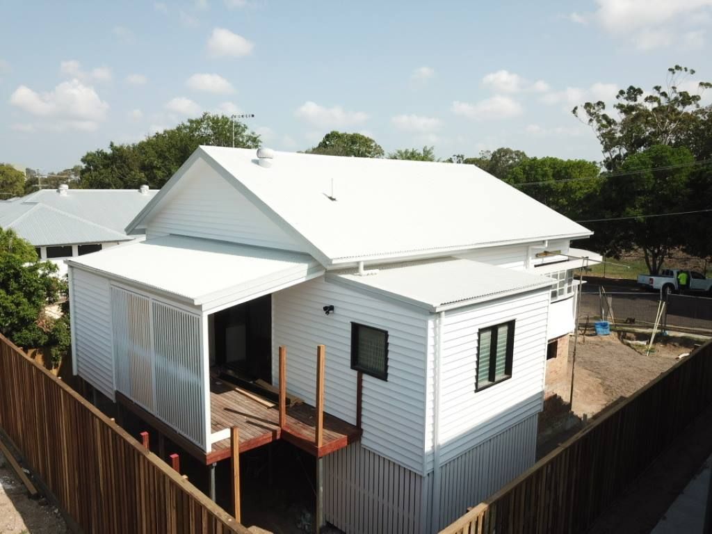 A White House With A Wooden Fence Around It — Harrison Development Group In Surfers Paradise, QLD