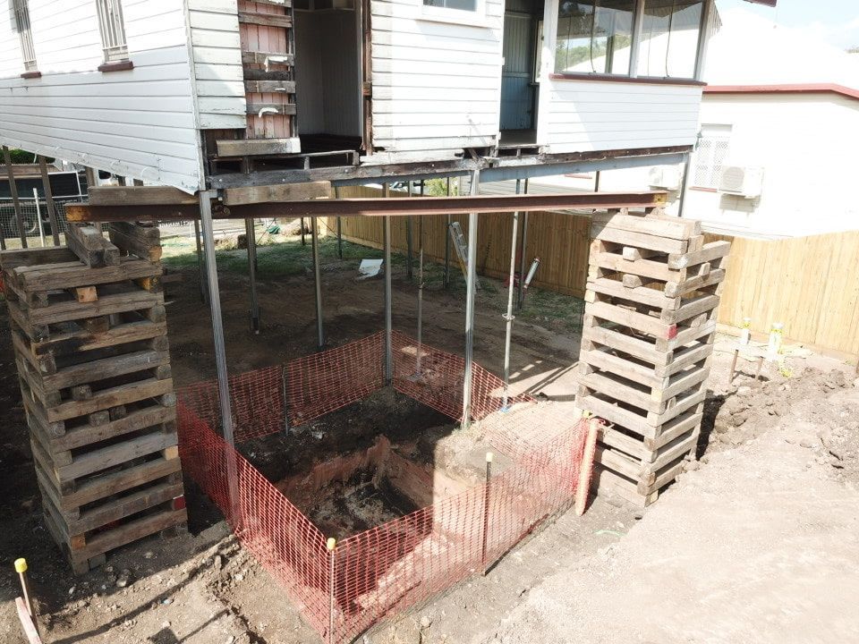 There Is A Hole In The Ground In Front Of A House That Is Being Built — Harrison Development Group In Surfers Paradise, QLD