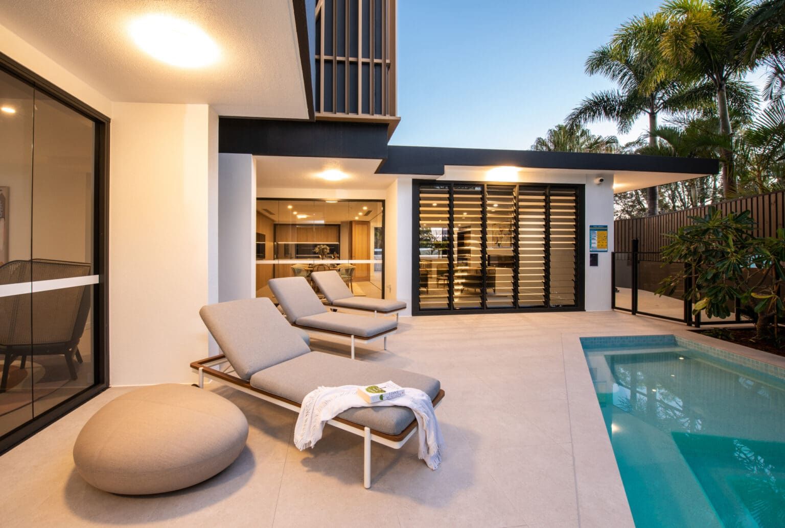 A Patio With Lounge Chairs And A Swimming Pool In Front Of A House — Harrison Development Group In Surfers Paradise, QLD
