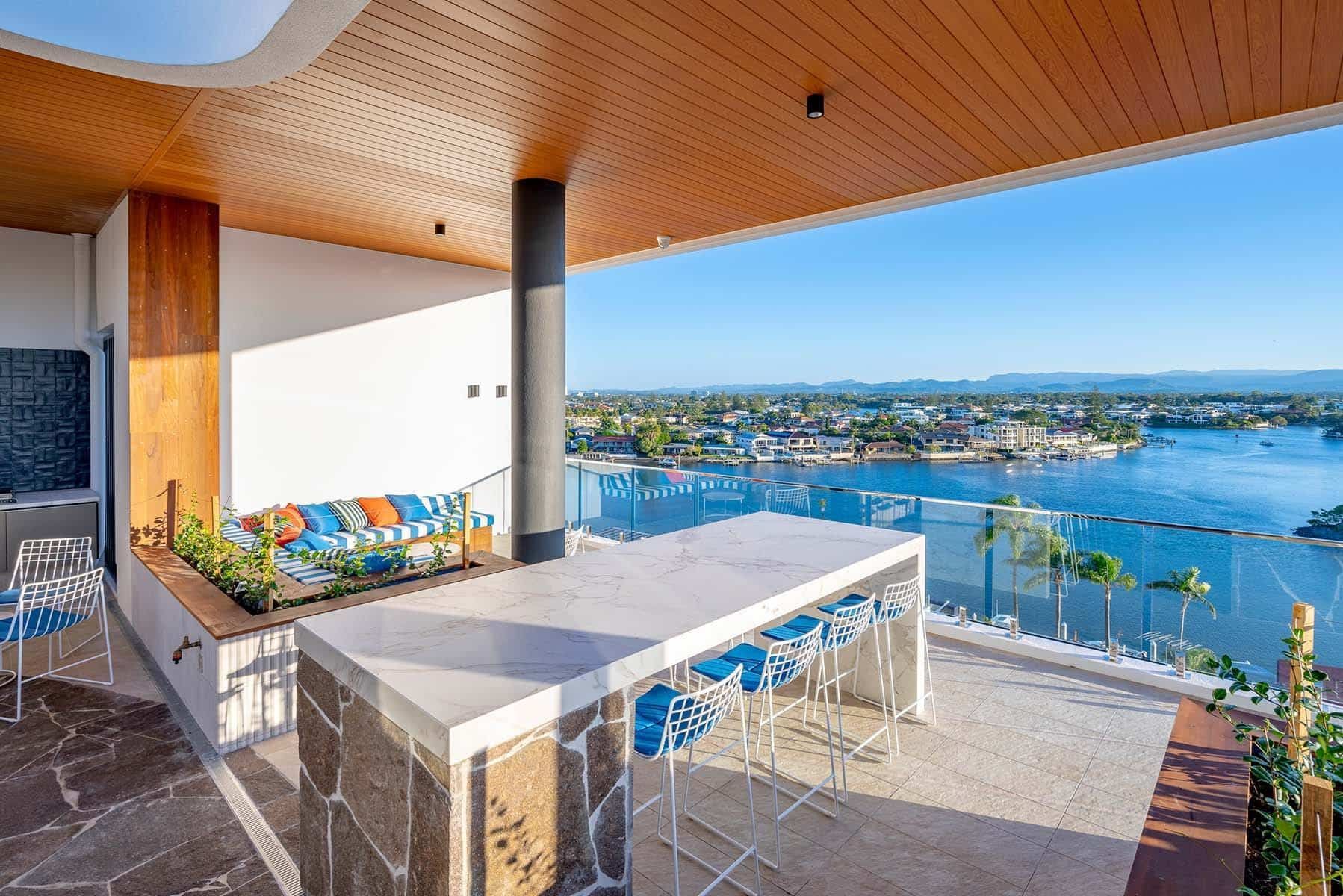 A Balcony With A Large Table And Chairs Overlooking A Body Of Water β Harrison Development Group In Surfers Paradise, QLD