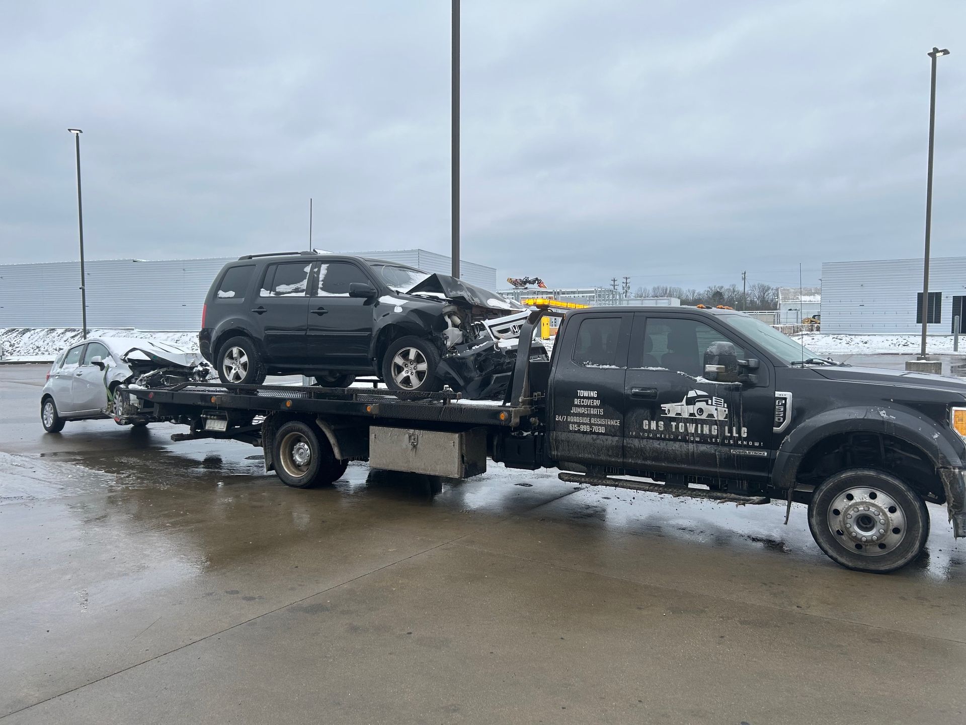 A tow truck is towing a car with a damaged front end.