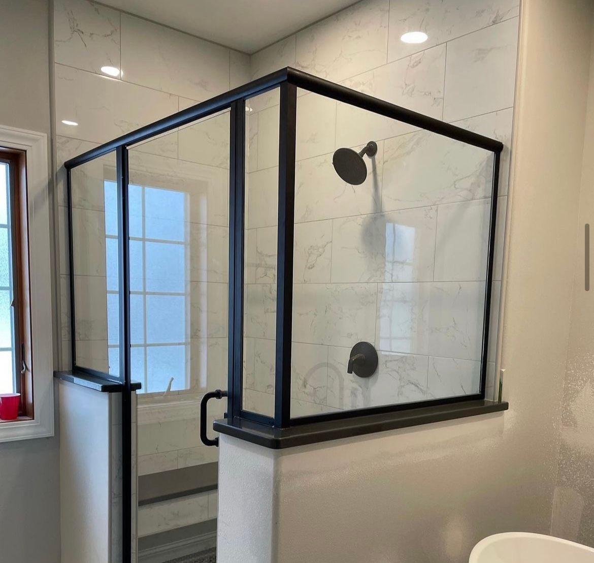 A bathroom with a shower stall and a window.