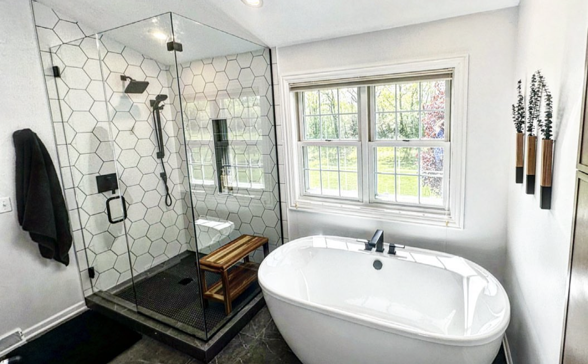 A bathroom with a tub , shower , toilet and window.