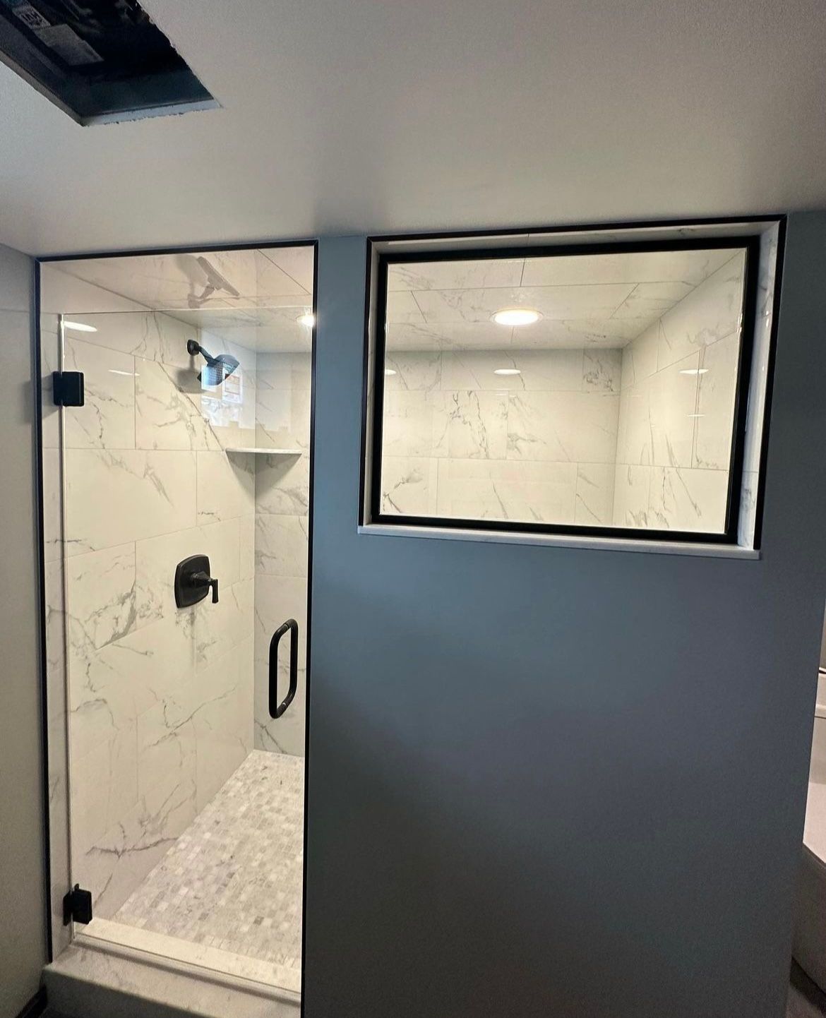 A bathroom with a walk in shower and a window.