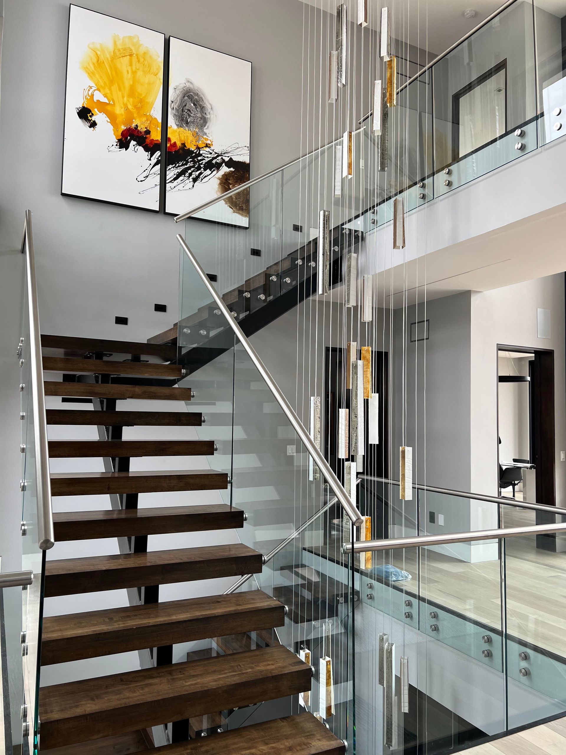A staircase with a glass railing and a painting on the wall.