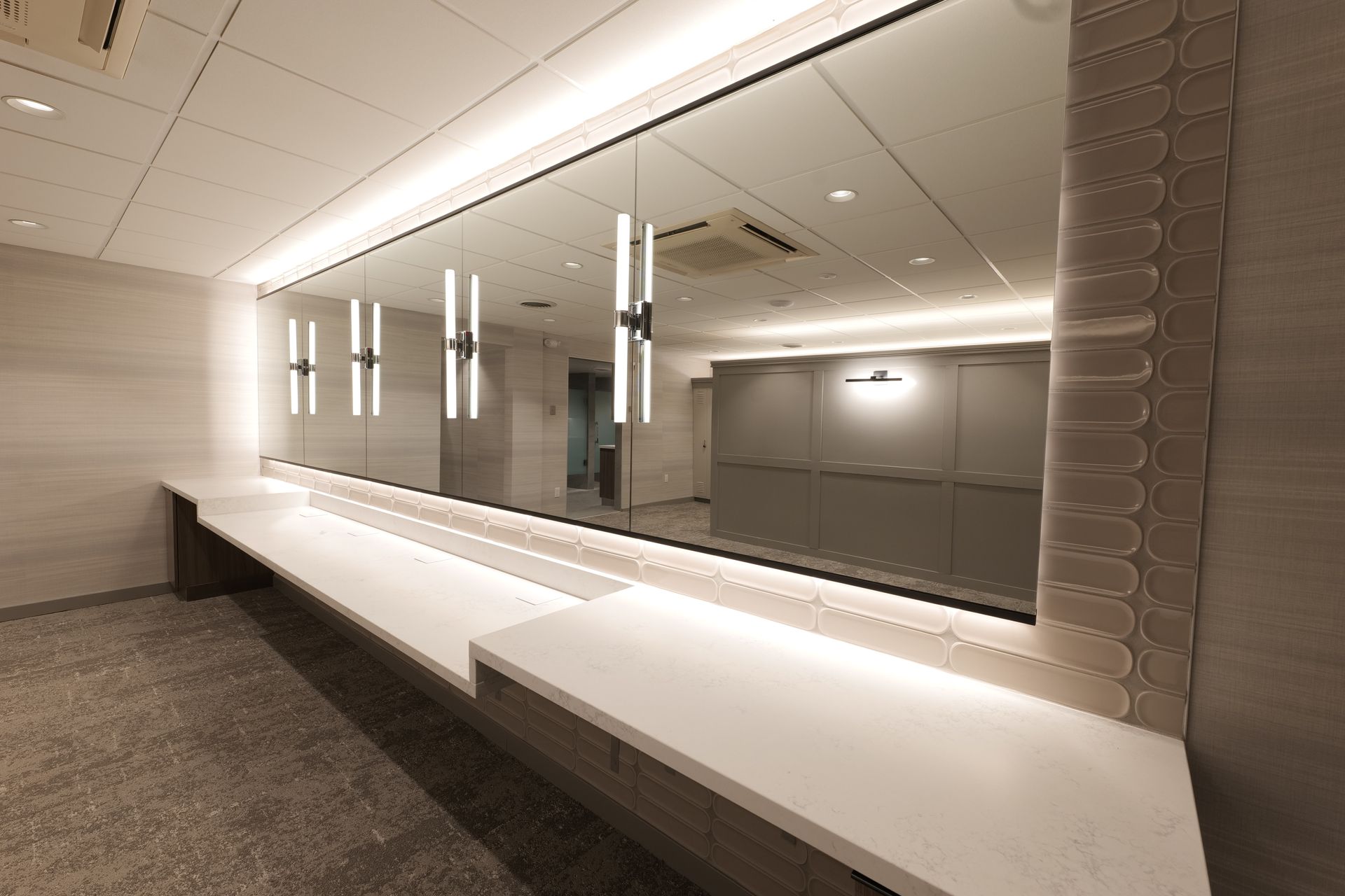 Modern bathroom with a long vanity, large mirror, and recessed lighting.