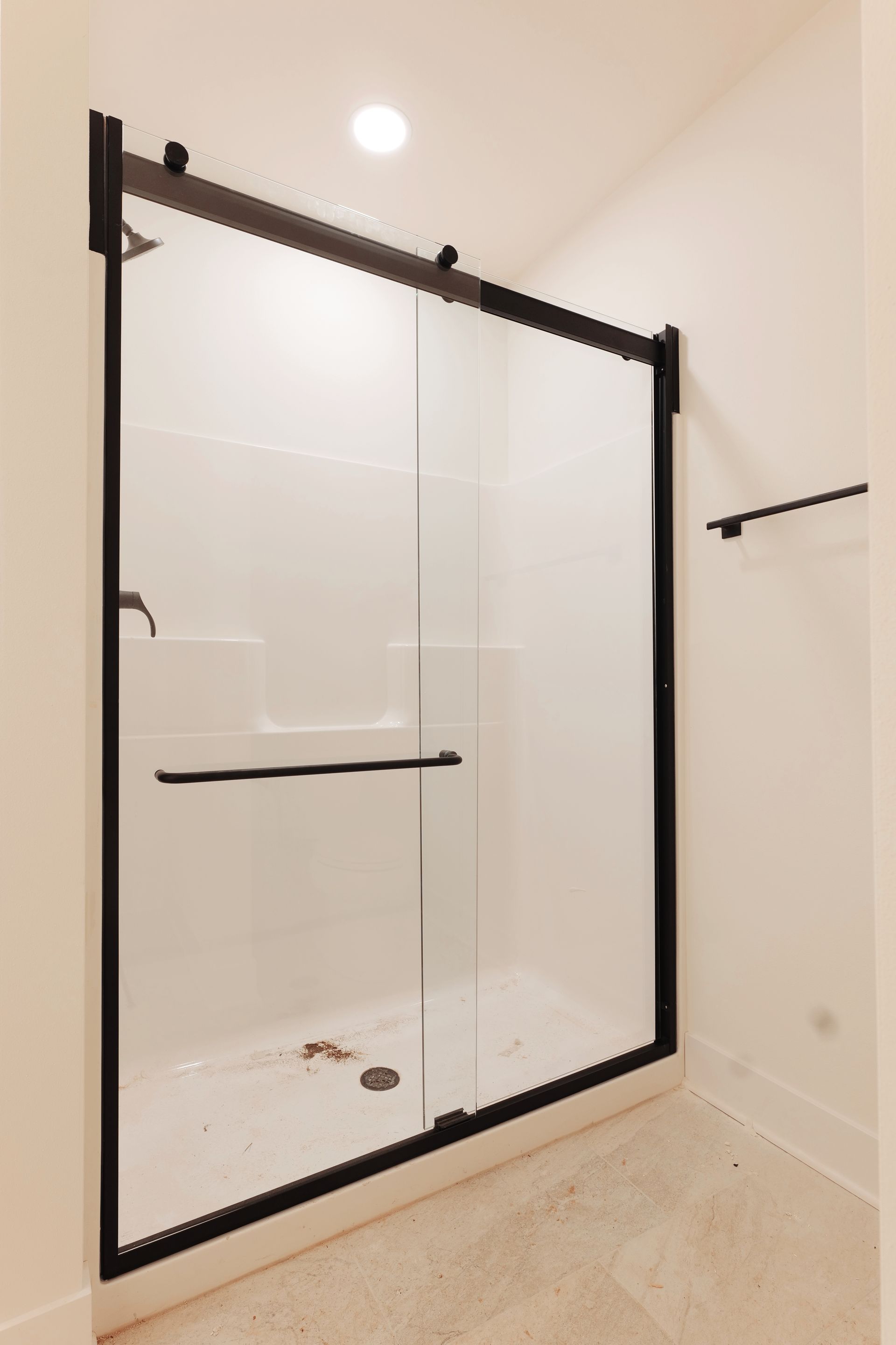 Gray-tiled shower with a glass door, a bench, and silver fixtures.