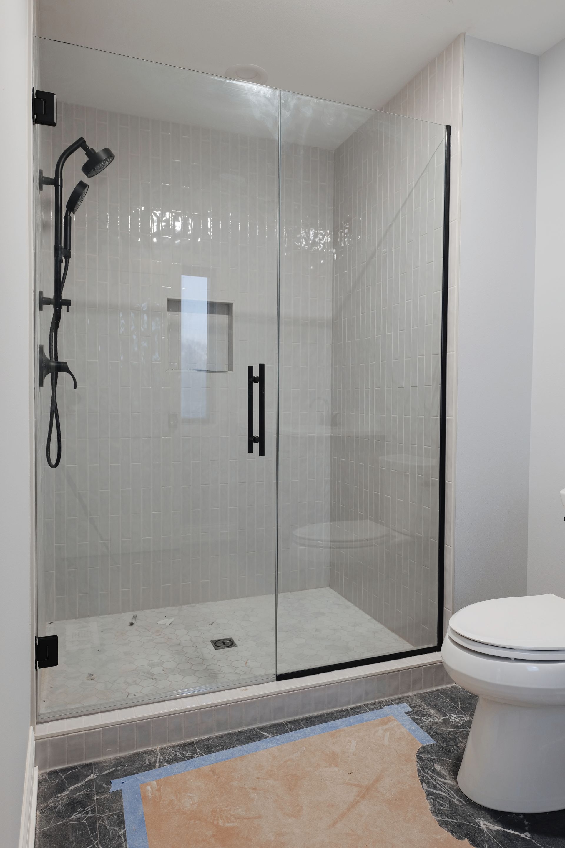 Modern bathroom with a glass shower enclosure and black fixtures.