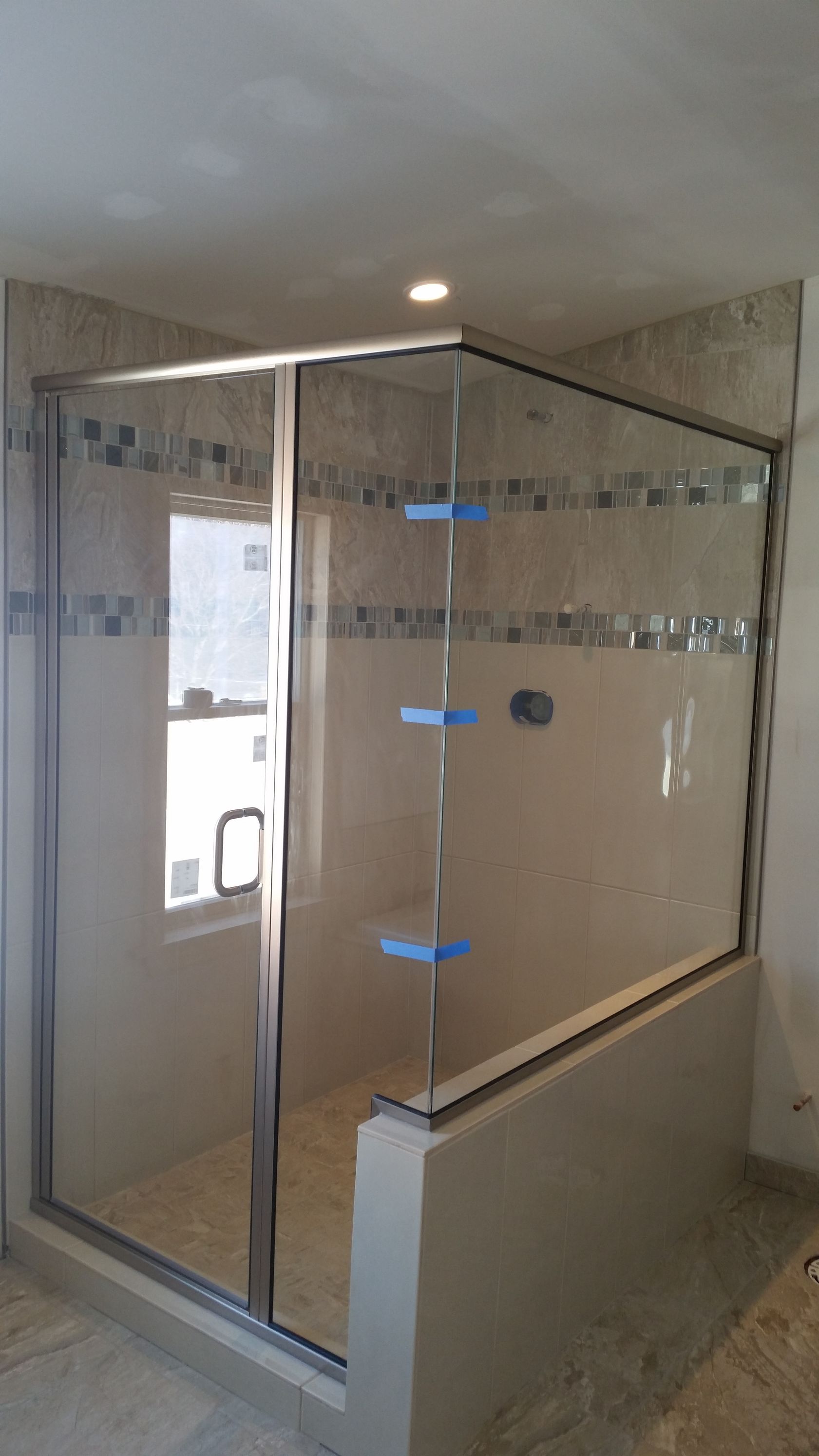 A bathroom with a glass shower door and a window.