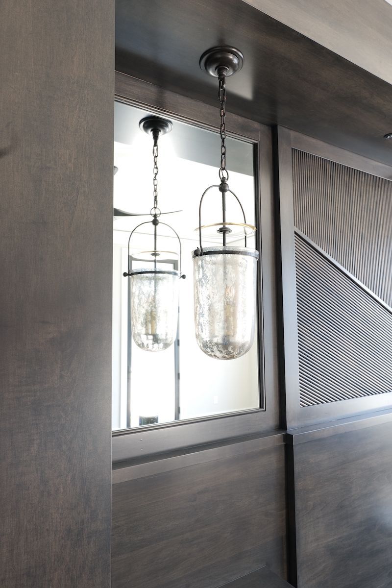 Two hanging pendant lights with textured glass shades, dark wood frame and accents.