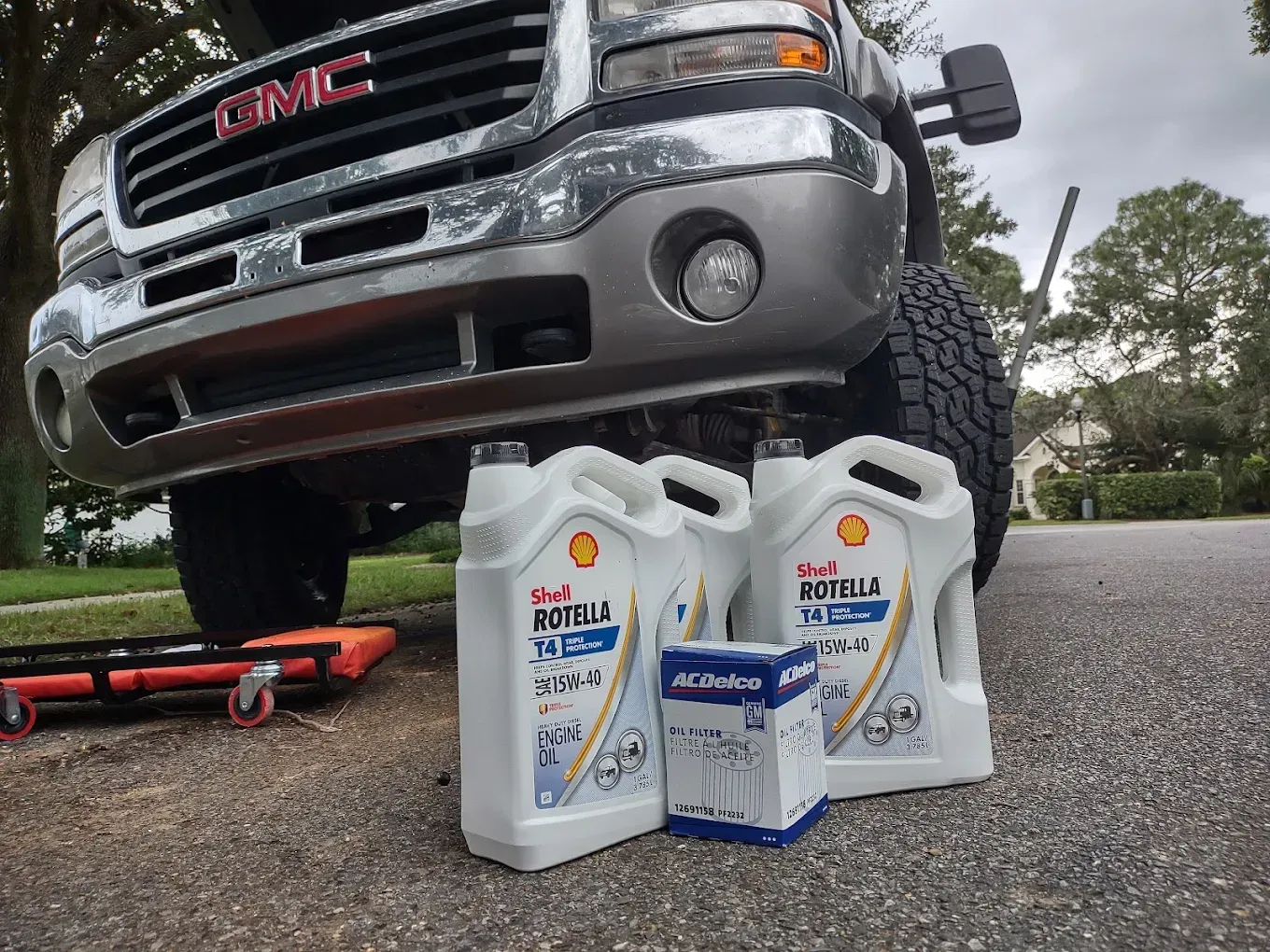 Silver GMC truck with oil containers and filter on asphalt.