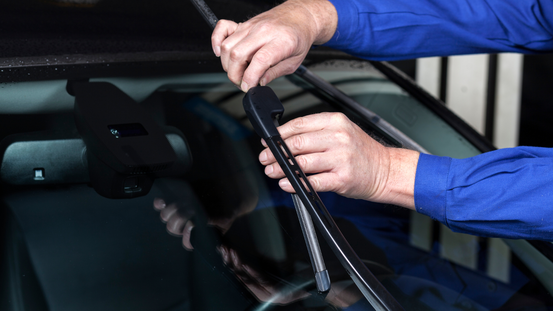 Person replacing a windshield wiper blade on a car.