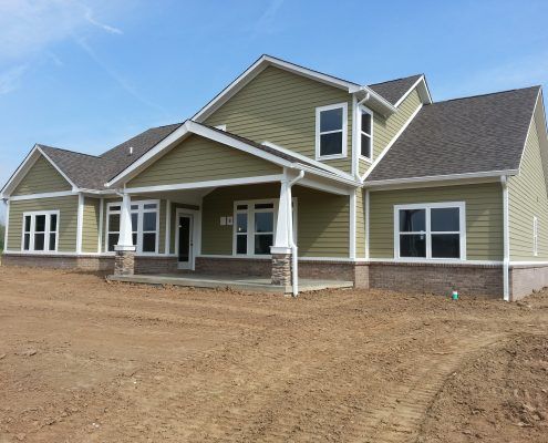 a large house with green siding and a gray roof