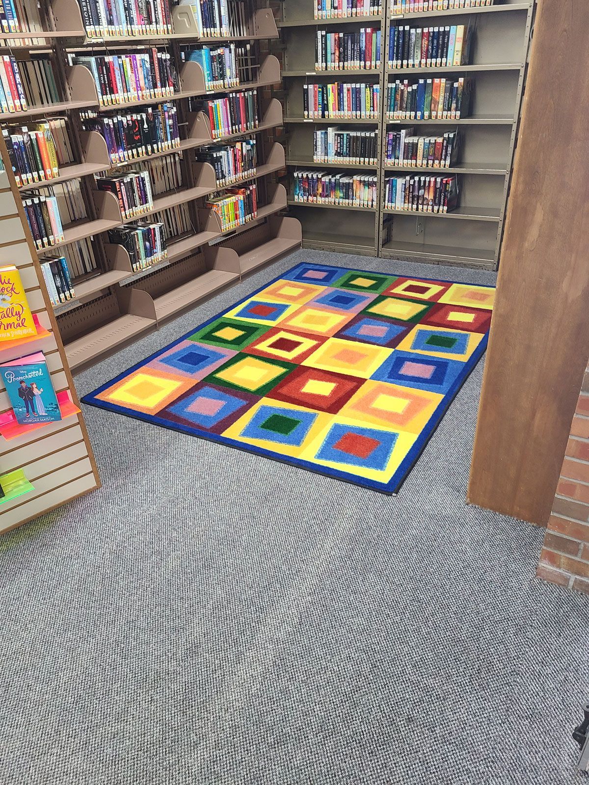 A colorful rug is on the floor in a library.