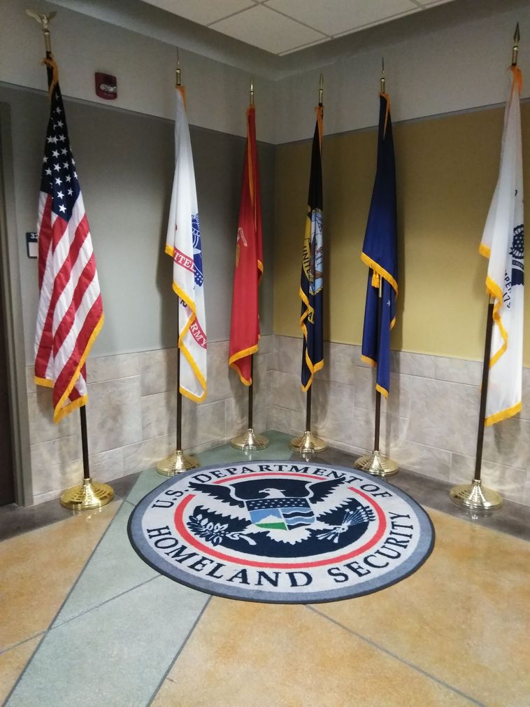 Two women are standing next to each other in front of flags in a room.