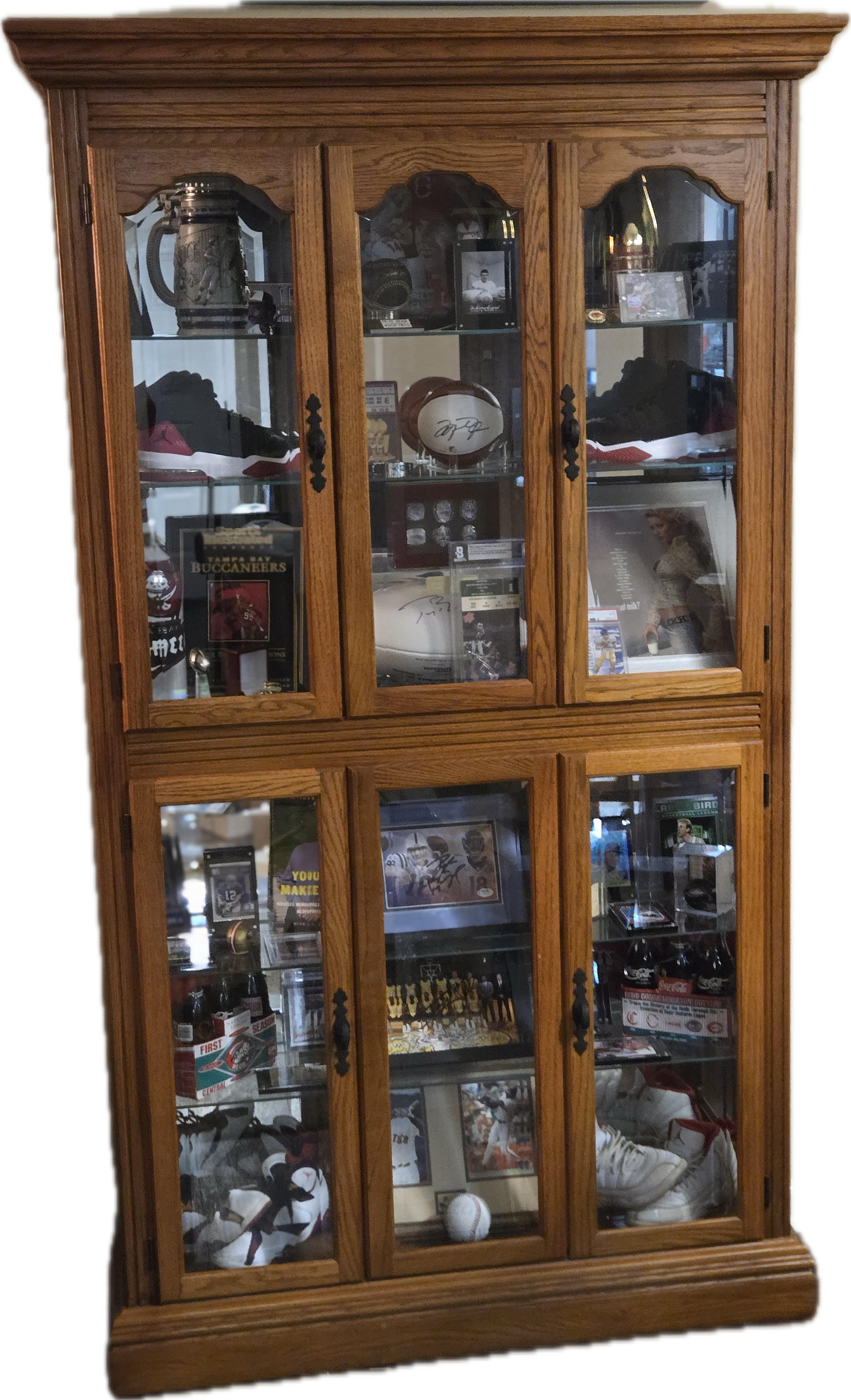 A wooden curio cabinet with glass doors and shelves filled with plates and other items.