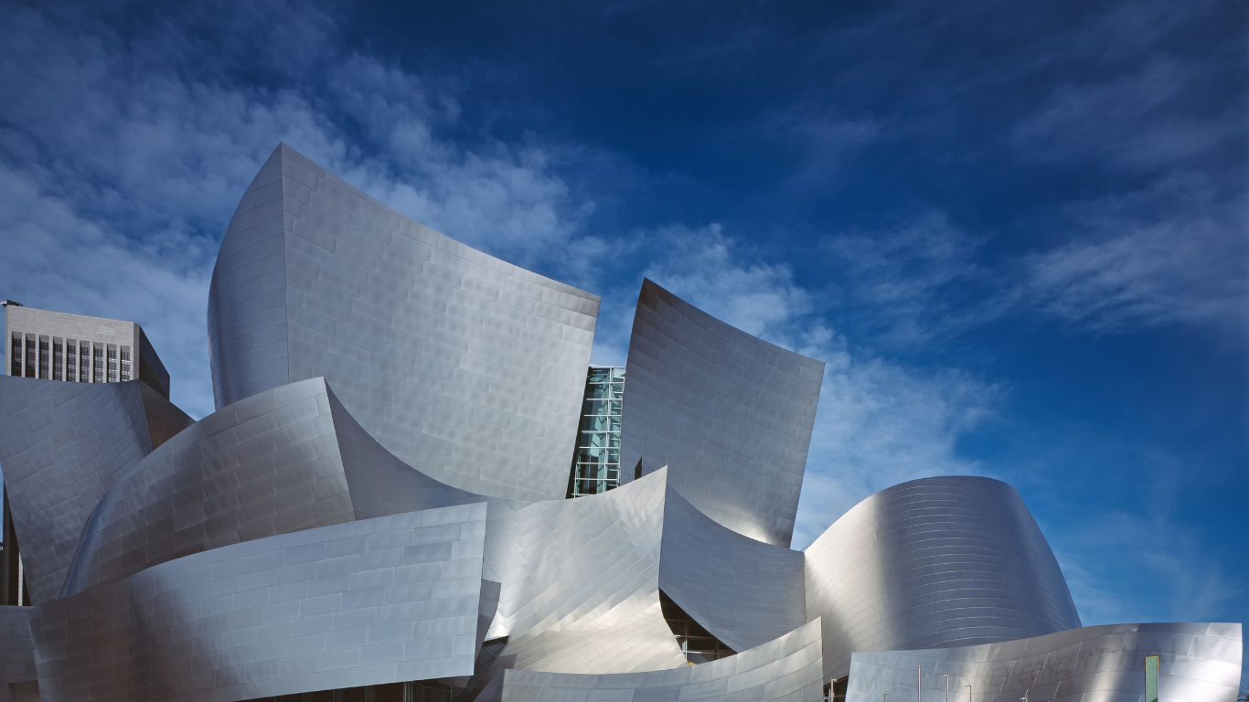 The iconic, sweeping silver stainless steel curves of the Walt Disney Concert Hall against a blue sky.