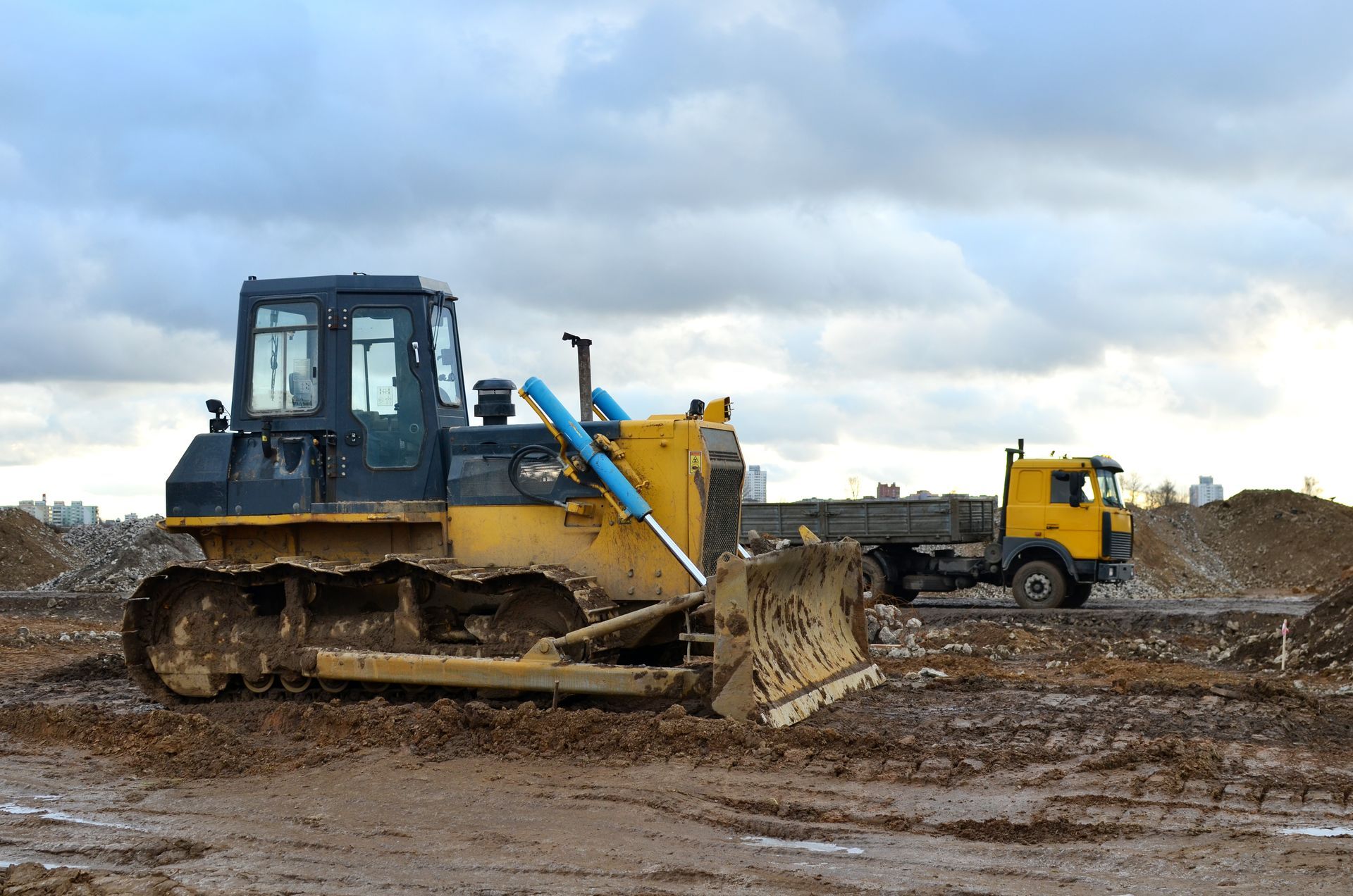 Bulldozer and dump truck operating on muddy construction site. Bulldozer and dump truck operating on muddy construction site.